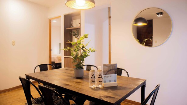 A dining area with a wooden table, black chairs, a potted plant, and a round mirror on the wall. - w Stylish Bright 2BR in Miraflores (Lima)