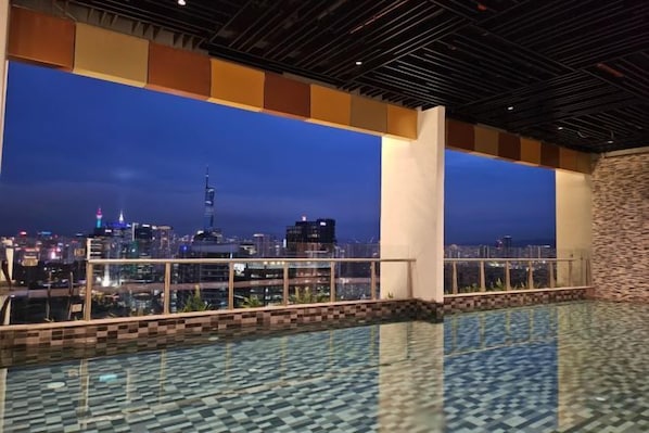 An indoor swimming pool with a cityscape view at dusk. - The Alfa Bangsar by City Keys (Kuala Lumpur)