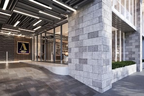 A modern building entrance with a stone facade, a logo on the wall, and a well-lit interior. - The Alfa Bangsar by City Keys (Kuala Lumpur)