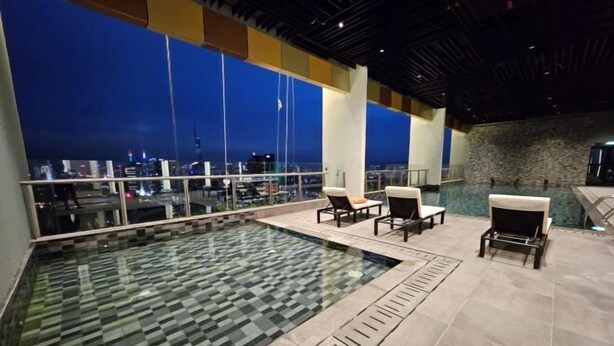 Une piscine sur le toit avec vue sur la ville, un espace extérieur aménagé et un mur en pierre.