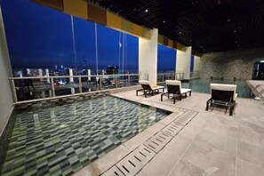 A rooftop pool with a city view, outdoor seating, and a stone wall. - The Alfa Bangsar by City Keys (Kuala Lumpur)