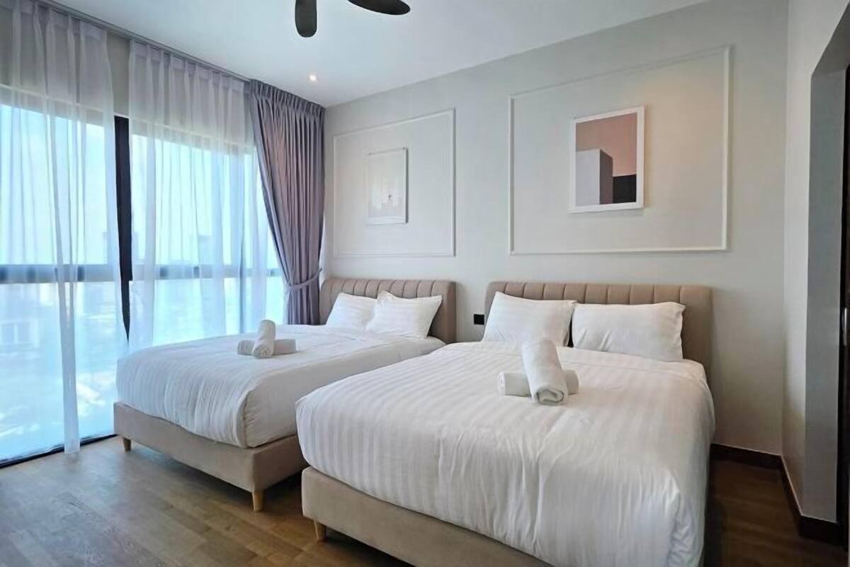 A hotel room with two beds, large windows, and a view.