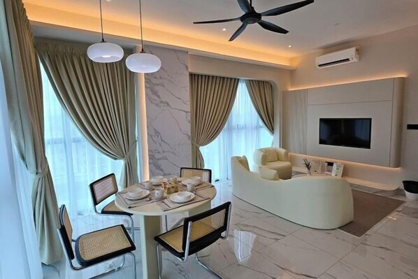A modern living room with a dining area, a sofa, a flat-screen TV, and a ceiling fan. - The Alfa Bangsar by City Keys (Kuala Lumpur)