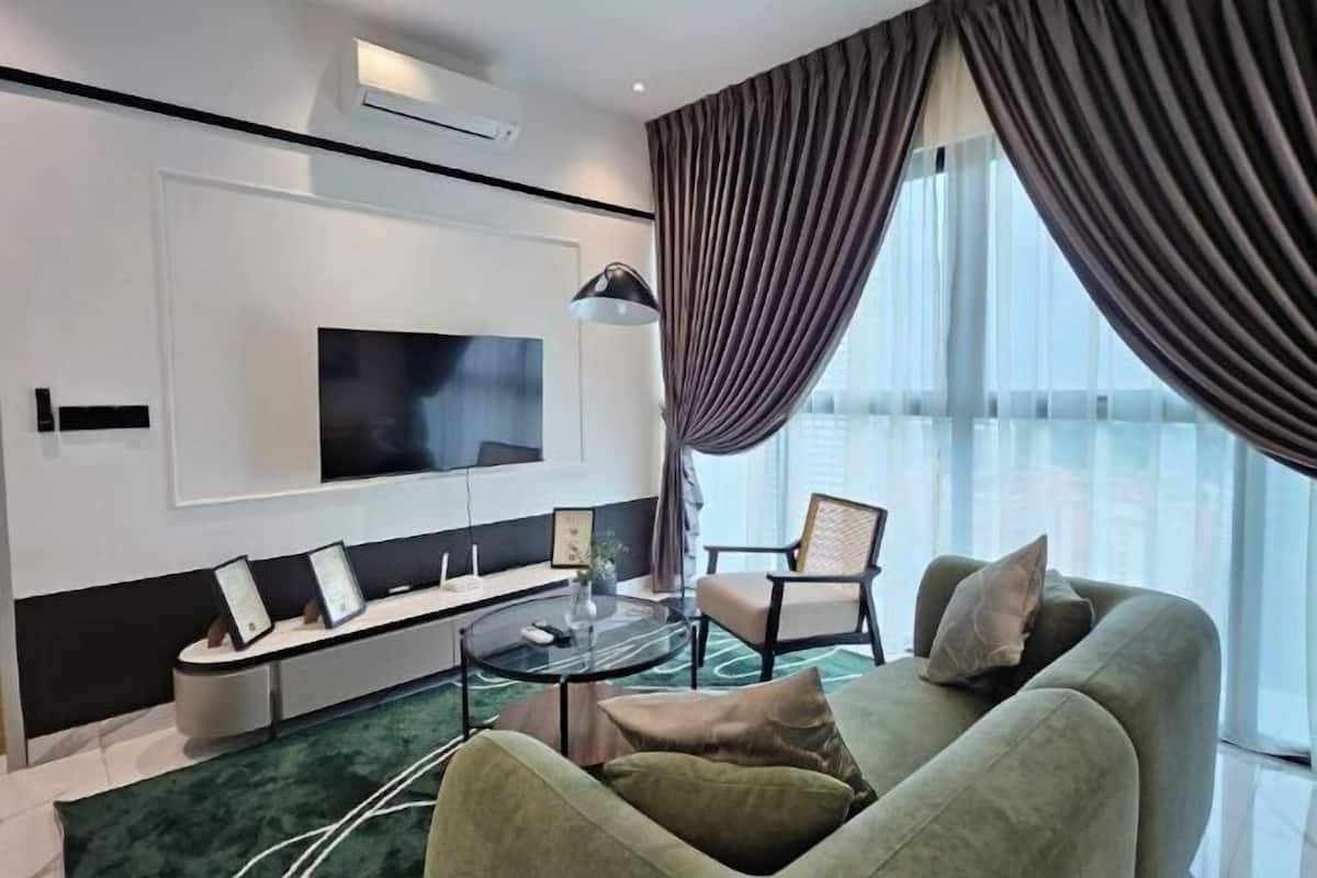 A modern living room with a flat-screen TV, a sofa, a chair, and a coffee table.