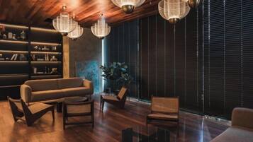Una sala de estar moderna con techo de madera, un sofá, sillas, una mesa de centro y una estantería.