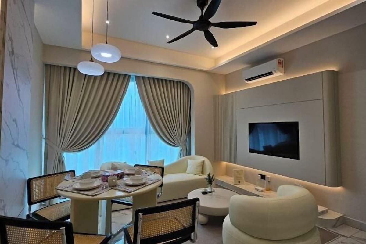 A modern hotel room with a dining area, a sofa, a TV, and a ceiling fan.
