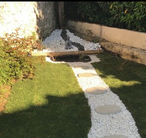 Un sendero en el jardín con piedras y un banco de madera.