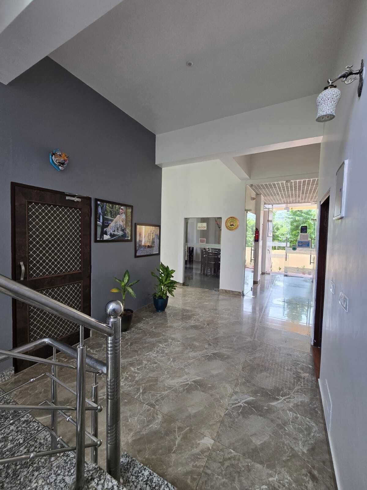A hallway with a marble floor, a staircase with metal railings, and a door with a metal grille.