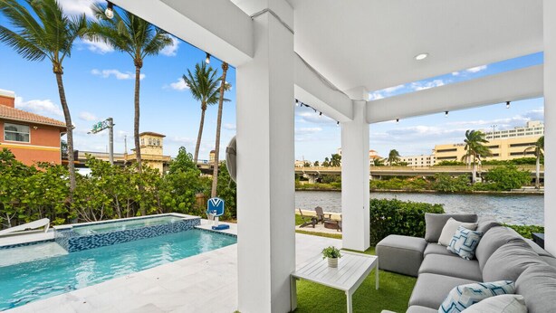 A covered outdoor area with a pool, a sofa, and a table.