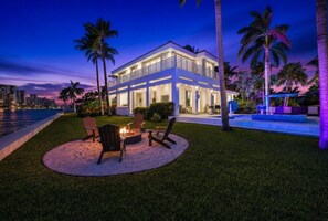 A modern house with a pool, outdoor seating, and palm trees.