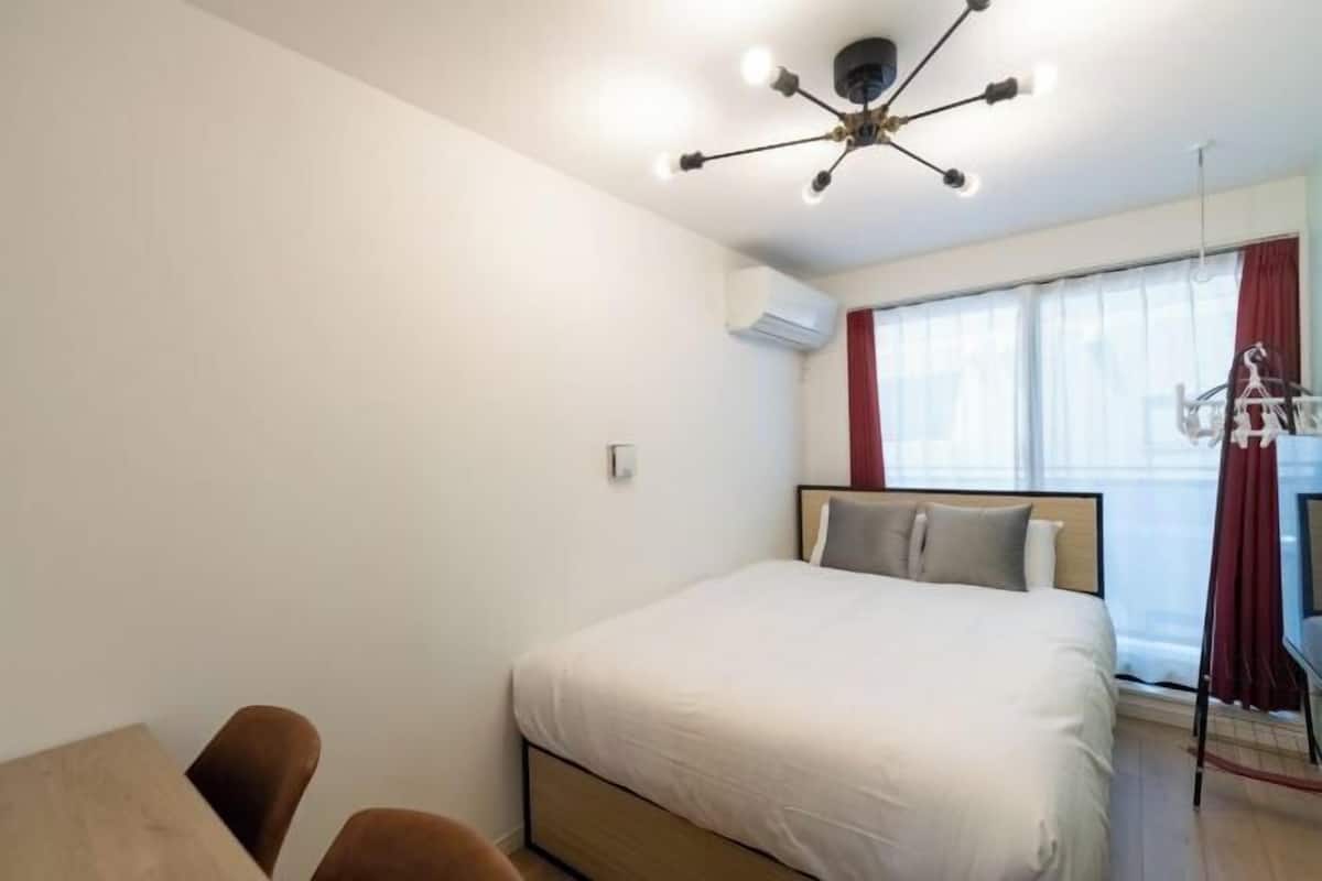 A bedroom with a bed, a desk, and a chair.