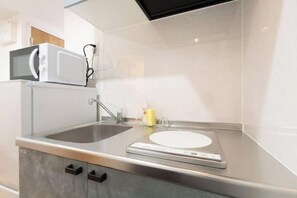 A modern kitchen with a microwave, sink, and digital scale. - Repure Higashimukojima Ekimae Residence II (Tokyo)