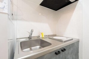 A modern kitchen with a stainless steel sink, a built-in scale, and a black range hood. - Repure Higashimukojima Ekimae Residence II (Tokyo)