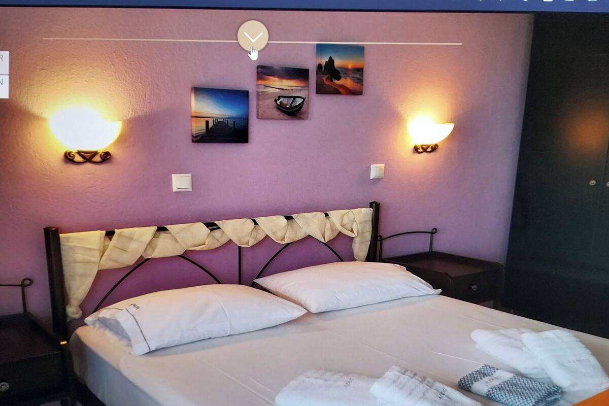 A hotel room with a bed, two wall-mounted lights, and three framed pictures on the wall.