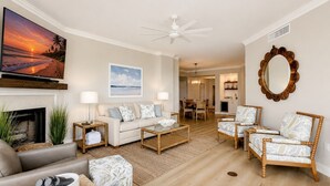 A living room with a sofa, coffee table, and chairs, a fireplace, and a dining area in the background. - 1906 South Beach Club - Just a Few Steps from Pool Days and Beach Waves! (Hilton Head Island)