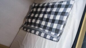 A bed with a white mattress and a black and white checkered pillow.