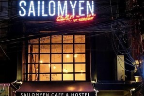 A building with a neon sign reading 'SAILOMYEN' and a window with the text 'SAILOMYEN CAFE & HOSTEL' below it. - Sailomyen Cafe and Hostel (Vientiane)