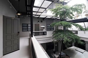 Un interior de varios niveles con una escalera, una puerta y un balcón con vistas a árboles.