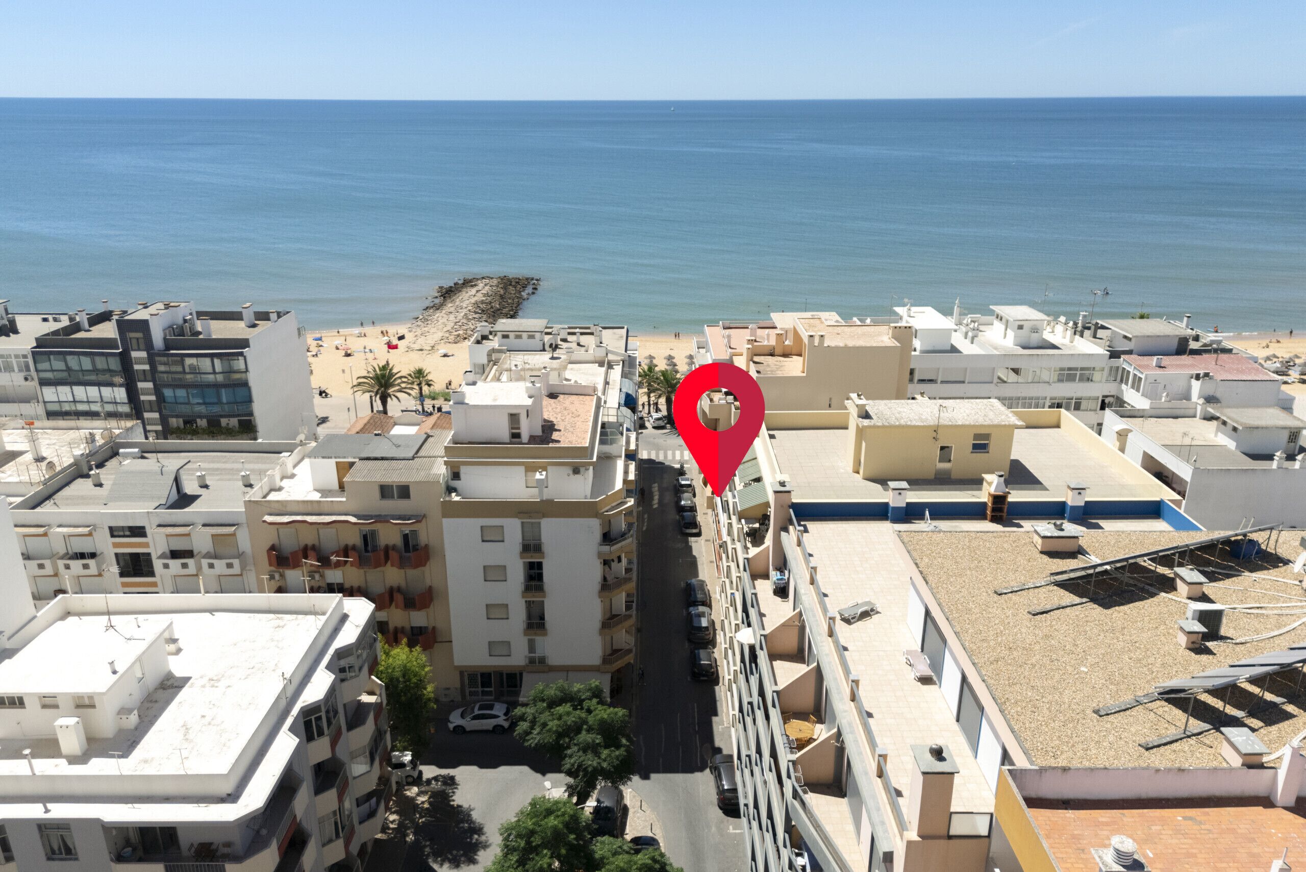 Ein Hochhaus-Hotel mit mehreren Stockwerken, einem Parkplatz und Blick auf Strand und Meer.