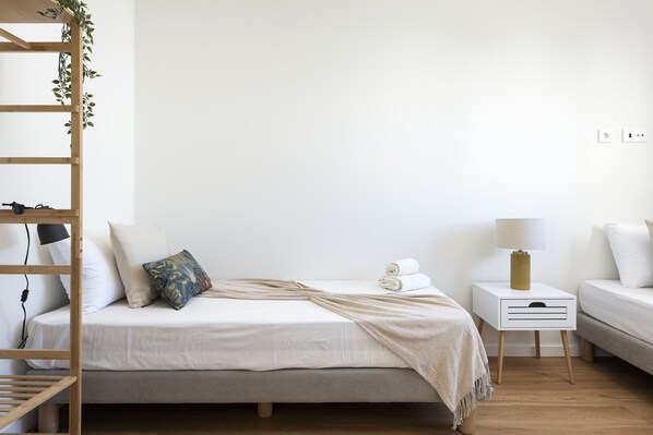 A bedroom with a bed, bedside table, lamp, and a wooden ladder.
