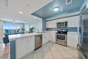 A modern kitchen with white cabinets, stainless steel appliances, and a large island.