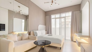 A modern hotel room with a large bed, a sofa, a round coffee table, and a desk. - Stylish Studio in Pearl House With Rooftop Pool (Dubai)