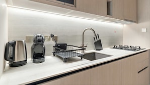 A modern kitchen with a Bosch microwave, a kettle, a coffee maker, a sink, and a gas stove. - Stylish Studio in Pearl House With Rooftop Pool (Dubai)