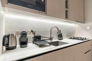 Una cucina moderna con un forno a microonde Bosch, un bollitore, una macchina del caffè, un lavello e un piano cottura a gas.