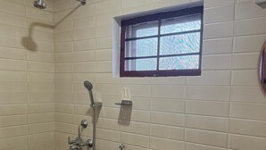 A bathroom with a toilet, bidet, and shower. There is a window above the toilet. - BLISS STAYS (Kanayannur)