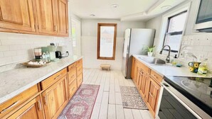 Een moderne keuken met houten kastjes, een inbouwoven en een raam boven de gootsteen.
