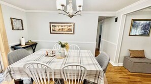 A dining room with a table covered in a plaid tablecloth, white chairs, a chandelier, and framed artwork on the walls. - Spacious 5-bedroom house in lovely Amherst with Central AC, (Buffalo)