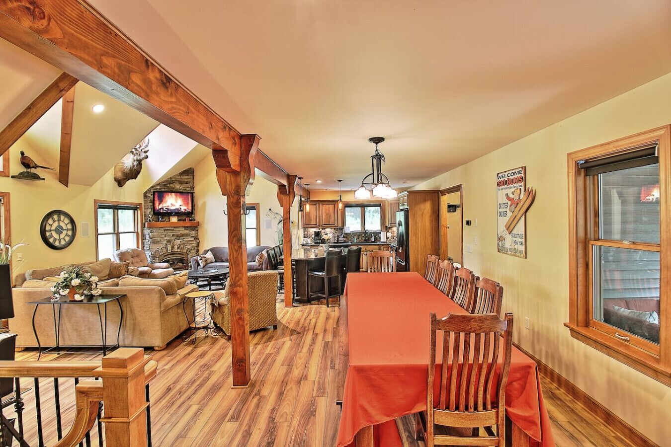 A spacious living area with a fireplace, a dining table with chairs, and a kitchen in the background.