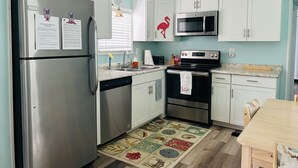 A compact kitchen with stainless steel appliances, white cabinets, and a patterned rug. - 272 Flamingo 2 Bedroom 2 Full Baths (Surfside Beach)