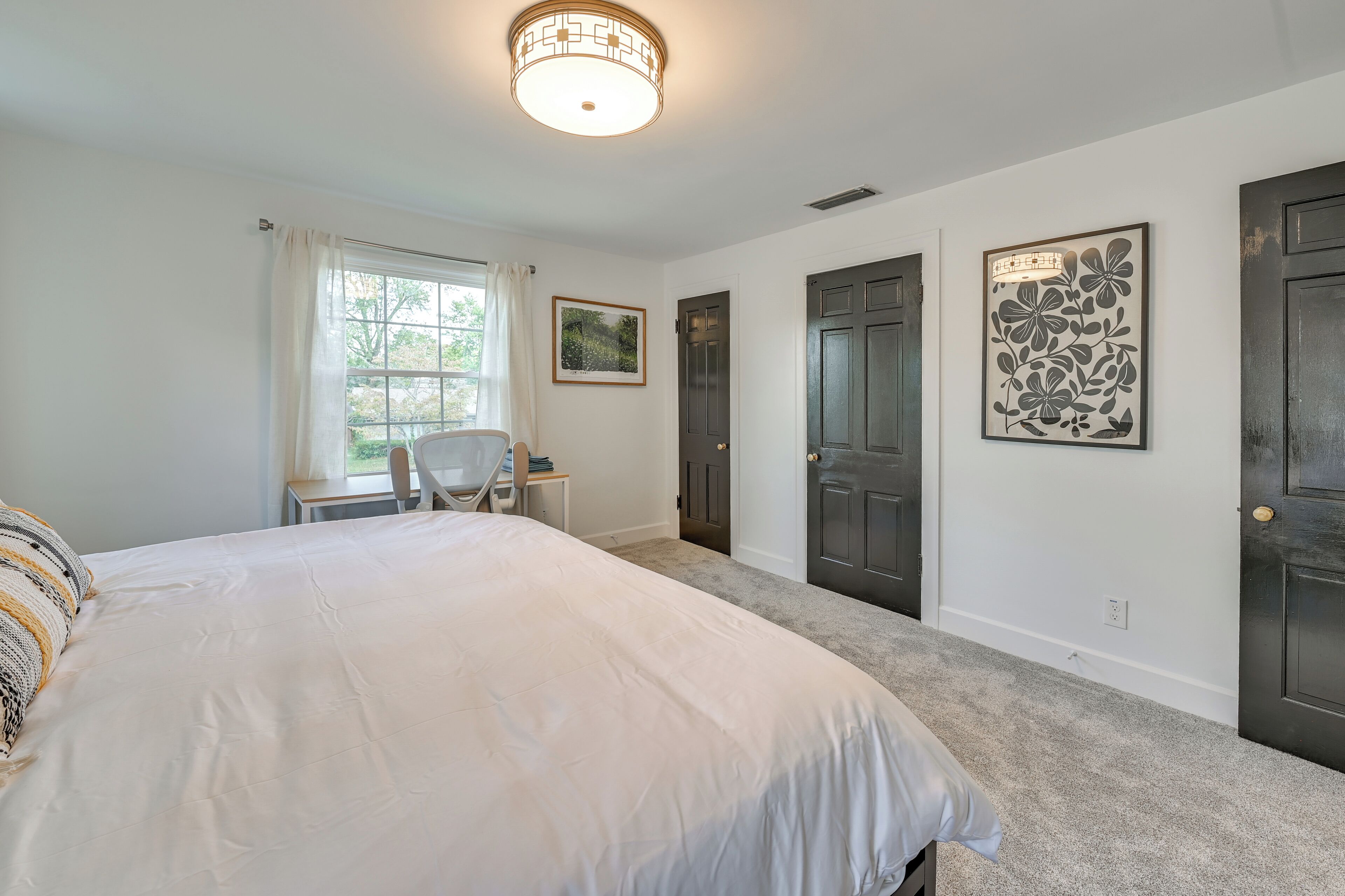 Une chambre avec un grand lit, un bureau et deux portes.