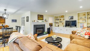 Una sala de estar con chimenea, sofás, comedor y televisor.