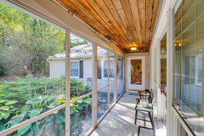 A covered porch with large windows, a wooden ceiling, and a view of a house and garden. - Near Main St & Festivals: Peaceful Keene Getaway! (Keene)
