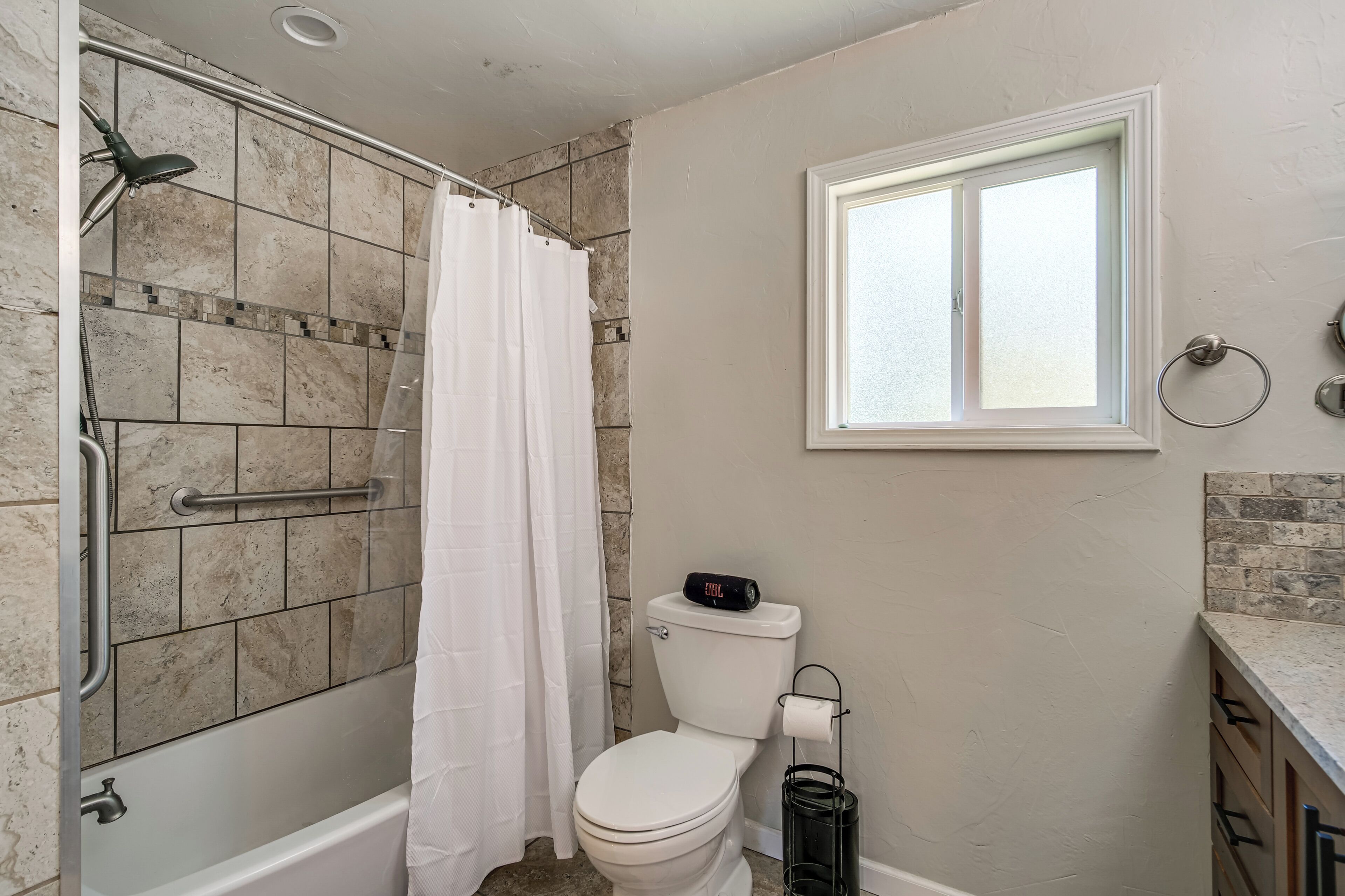 Un baño con ducha, inodoro y ventana.