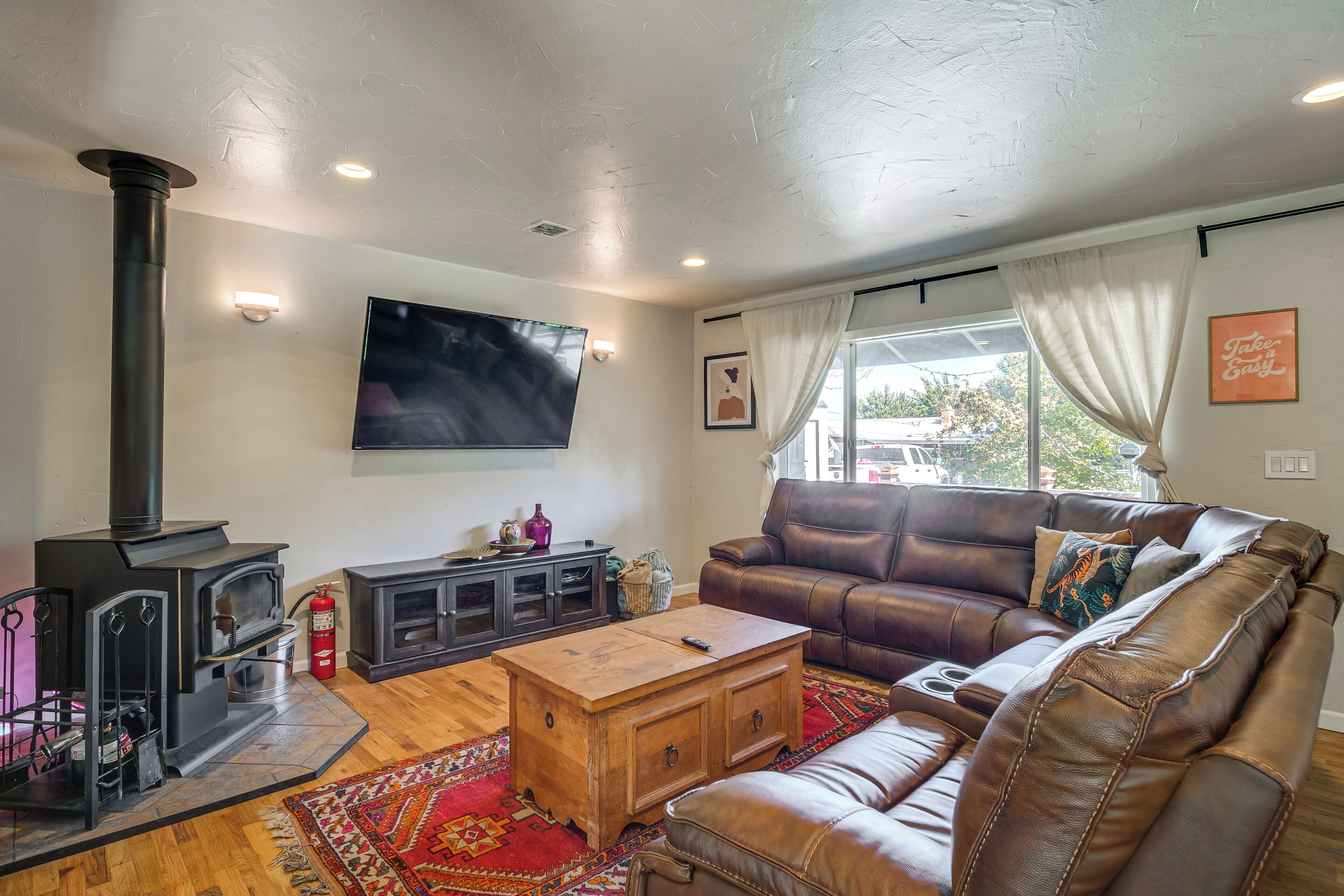 A living room with a large leather sofa, a wooden coffee table, a fireplace, and a television mounted on the wall.
