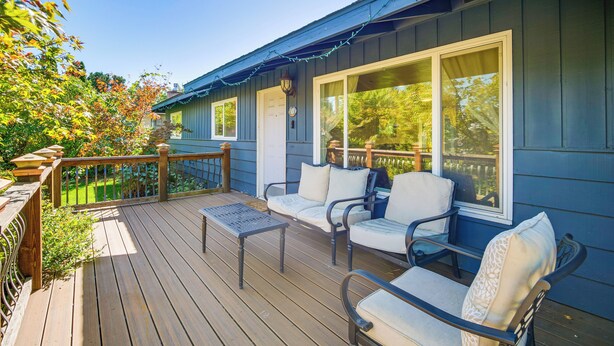 Une terrasse dotée de mobilier d’extérieur et offrant une vue sur une maison.