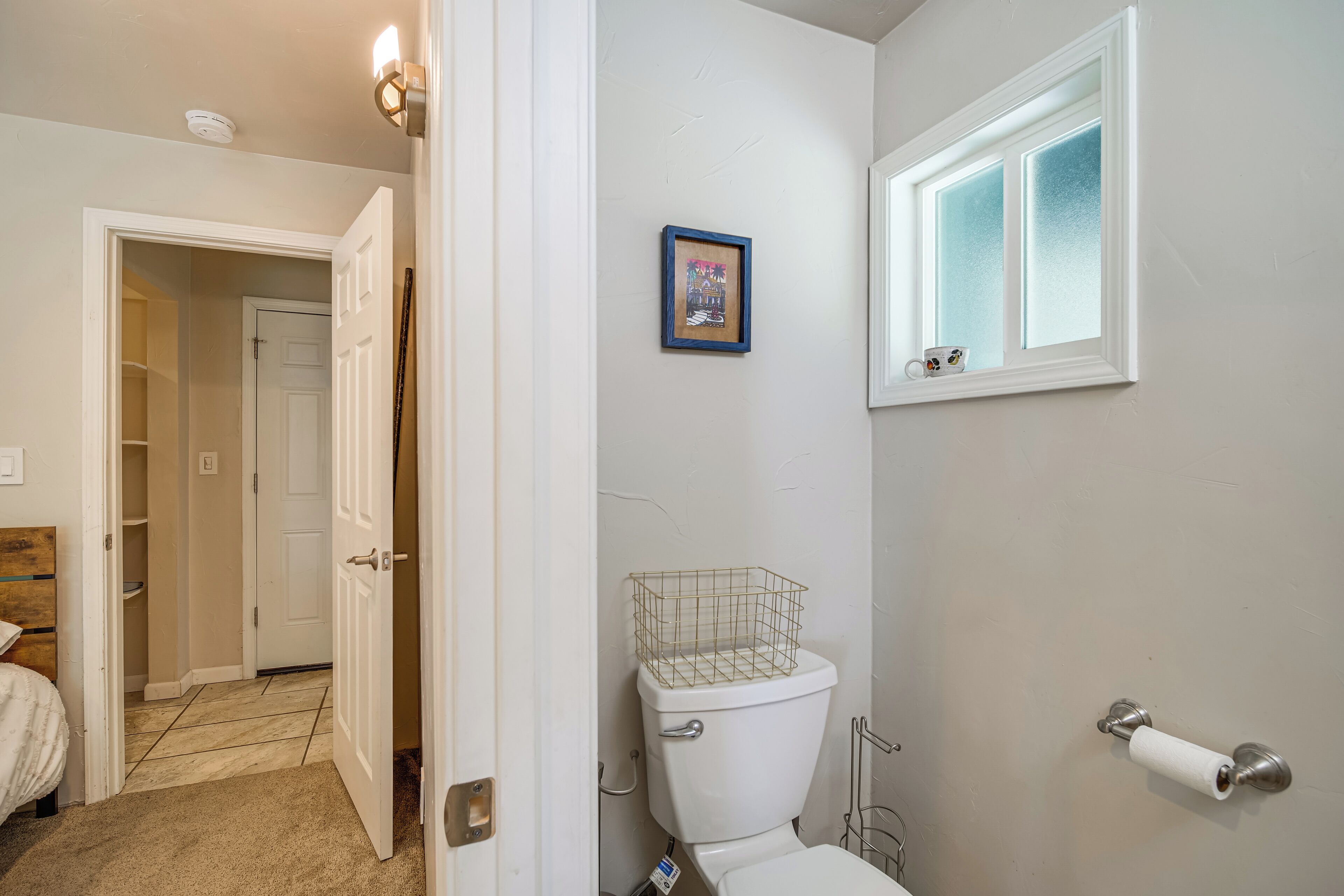 Et badeværelse med toilet, bruseområde og et vindue.