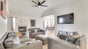 A spacious living room with a fireplace, leather sofas, a ceiling fan, and a flat-screen TV mounted on the wall. - Fenced-in Yard: Family Home 4 Mi to Dtwn Killeen! (Killeen)