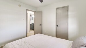 A bedroom with a bed, a ceiling fan, and a door leading to a bathroom. - Fenced-in Yard: Family Home 4 Mi to Dtwn Killeen! (Killeen)
