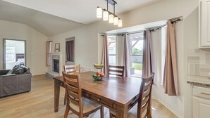 A dining area with a wooden table, chairs, a fruit bowl, and a hanging light fixture. - Fenced-in Yard: Family Home 4 Mi to Dtwn Killeen! (Killeen)
