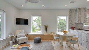 A modern living room with a sofa, a coffee table, a dining table with chairs, a TV mounted on the wall, and a kitchen area with a countertop and cabinets. - Walk to Gulf: Charming Santa Rosa Beach Duplex! (Santa Rosa Beach)