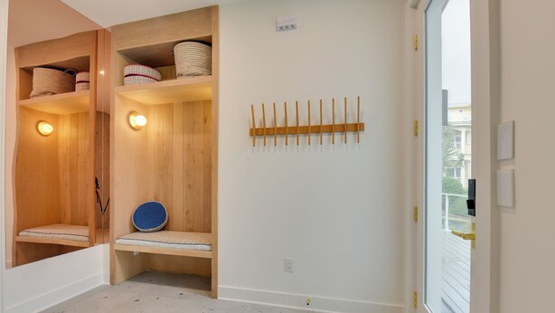 Une pièce avec des bancs en bois, un tapis bleu et un porte-objets fixé au mur.