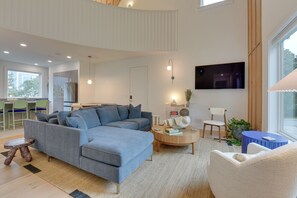A modern living room with a sectional sofa, a coffee table, and a TV mounted on the wall. - Stroll to Shore, Modern Santa Rosa Beach Duplex! (Santa Rosa Beach)