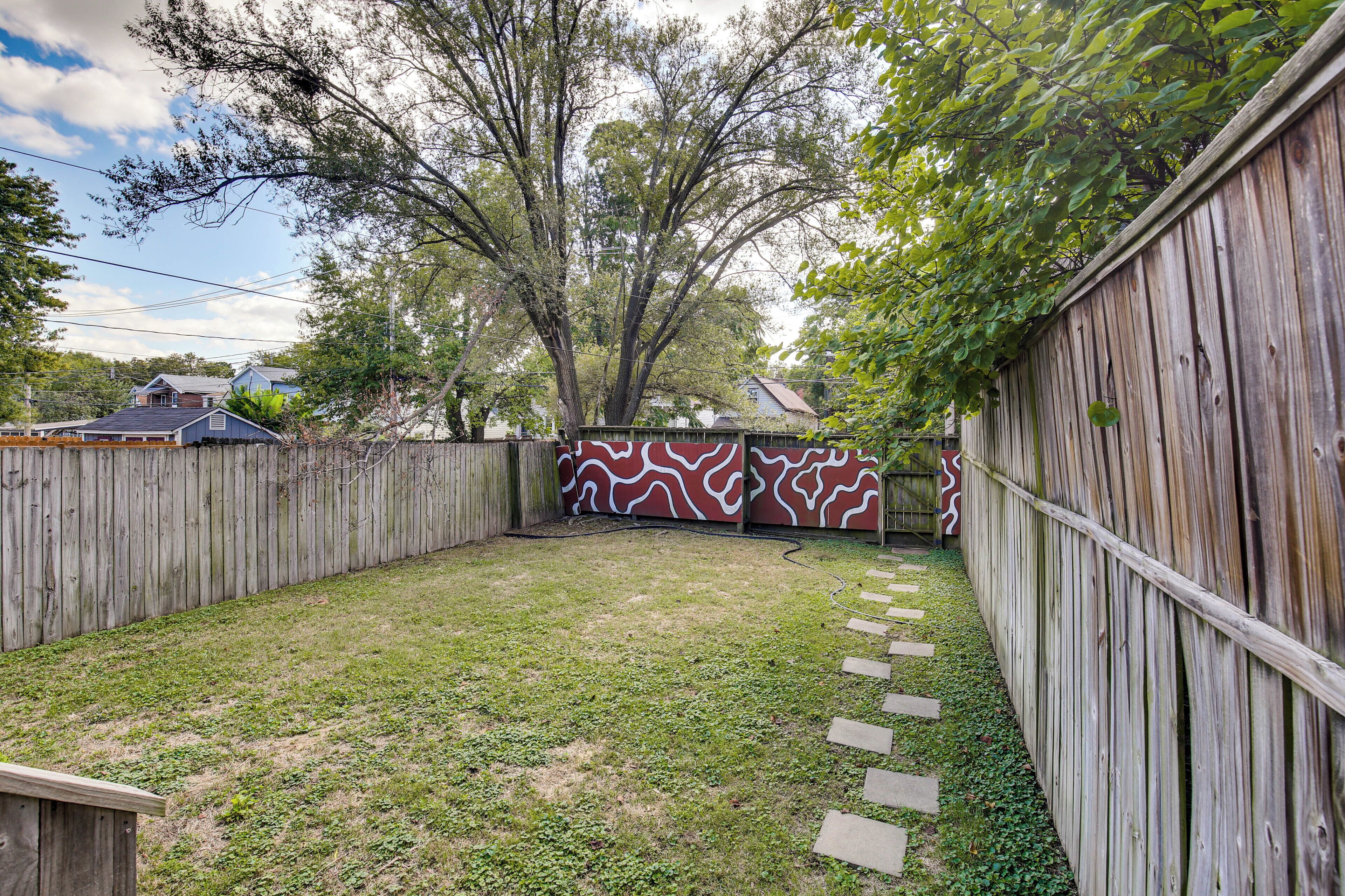 A backyard with a wooden fence, a grassy area, and a stepping stone path.