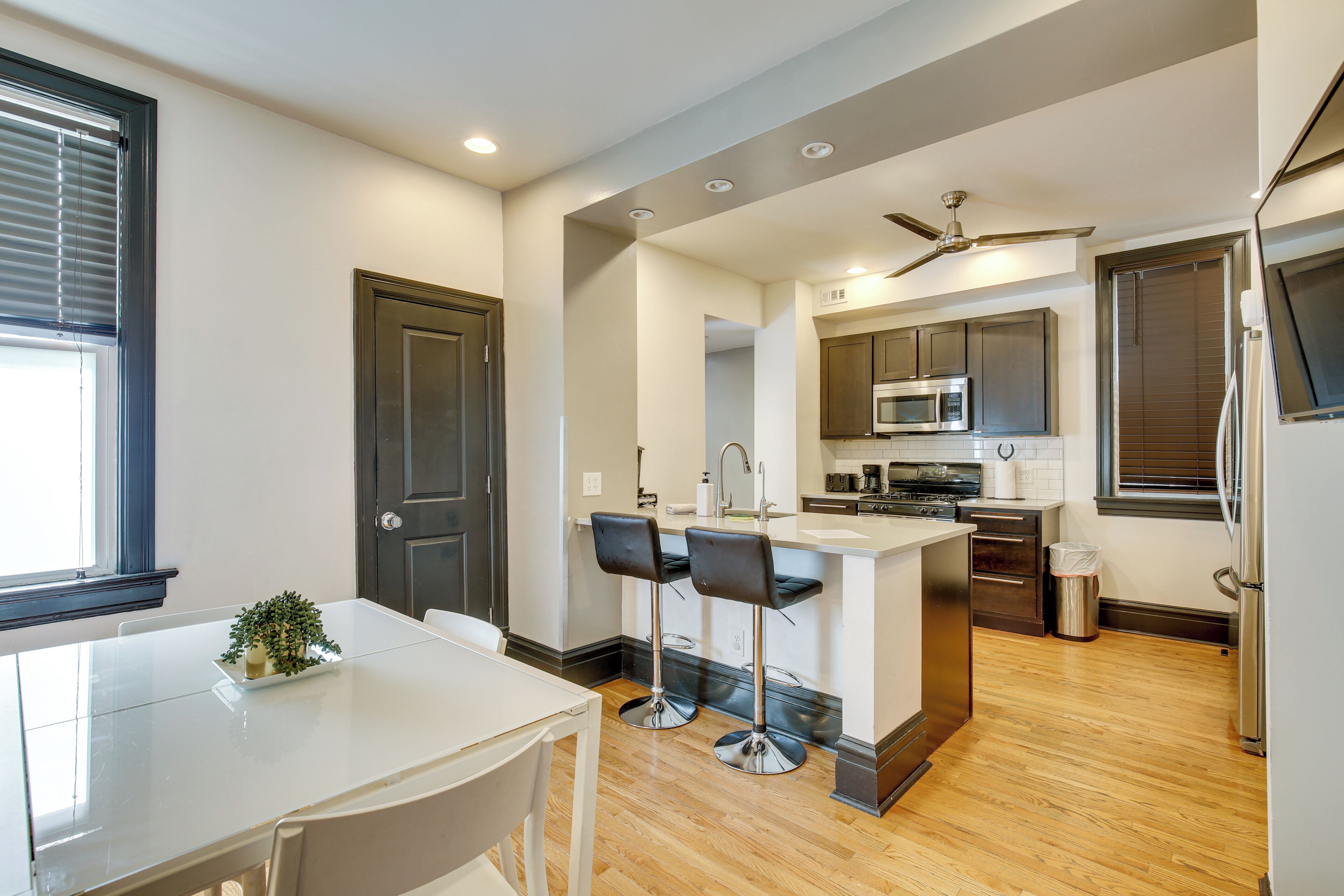 A modern kitchen with a central island, bar stools, and a dining table.