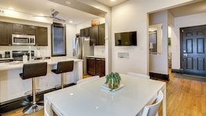 A modern kitchen with dark wooden cabinets, a white countertop, a stainless steel refrigerator, and a built-in microwave. There is a dining table with two chairs and a potted plant on it. - Walk to Tower Grove Park: St Louis Getaway (St. Louis)