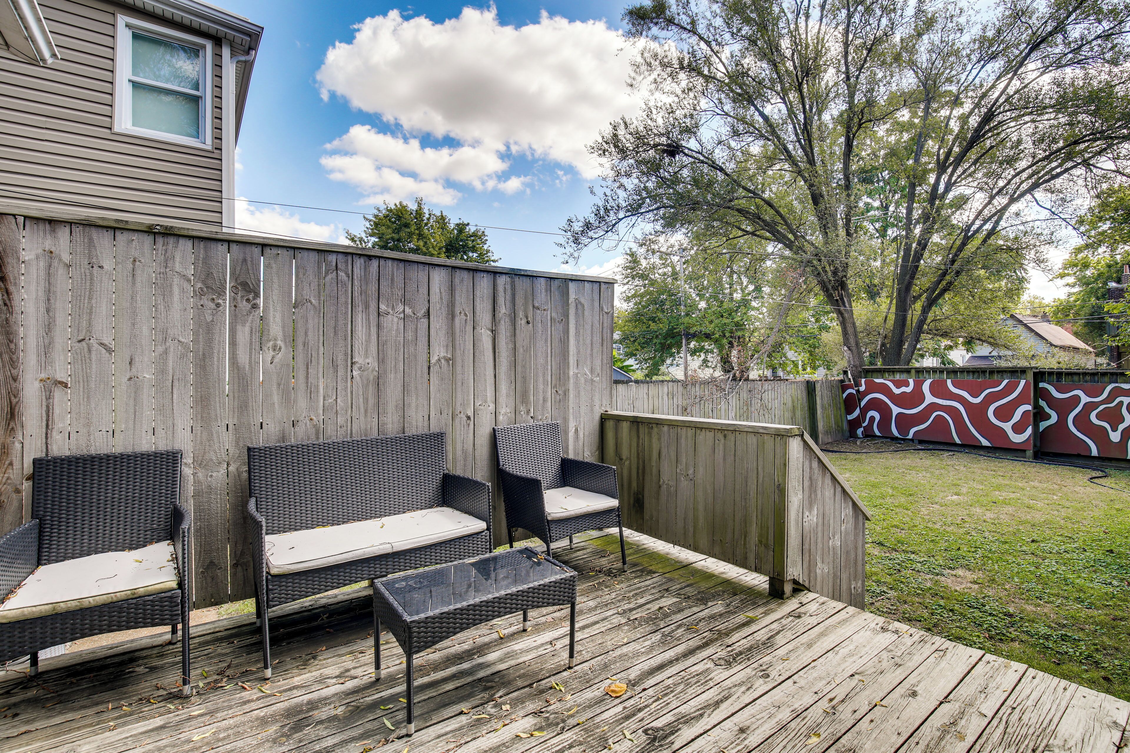 A wooden deck with wicker furniture and a small table.